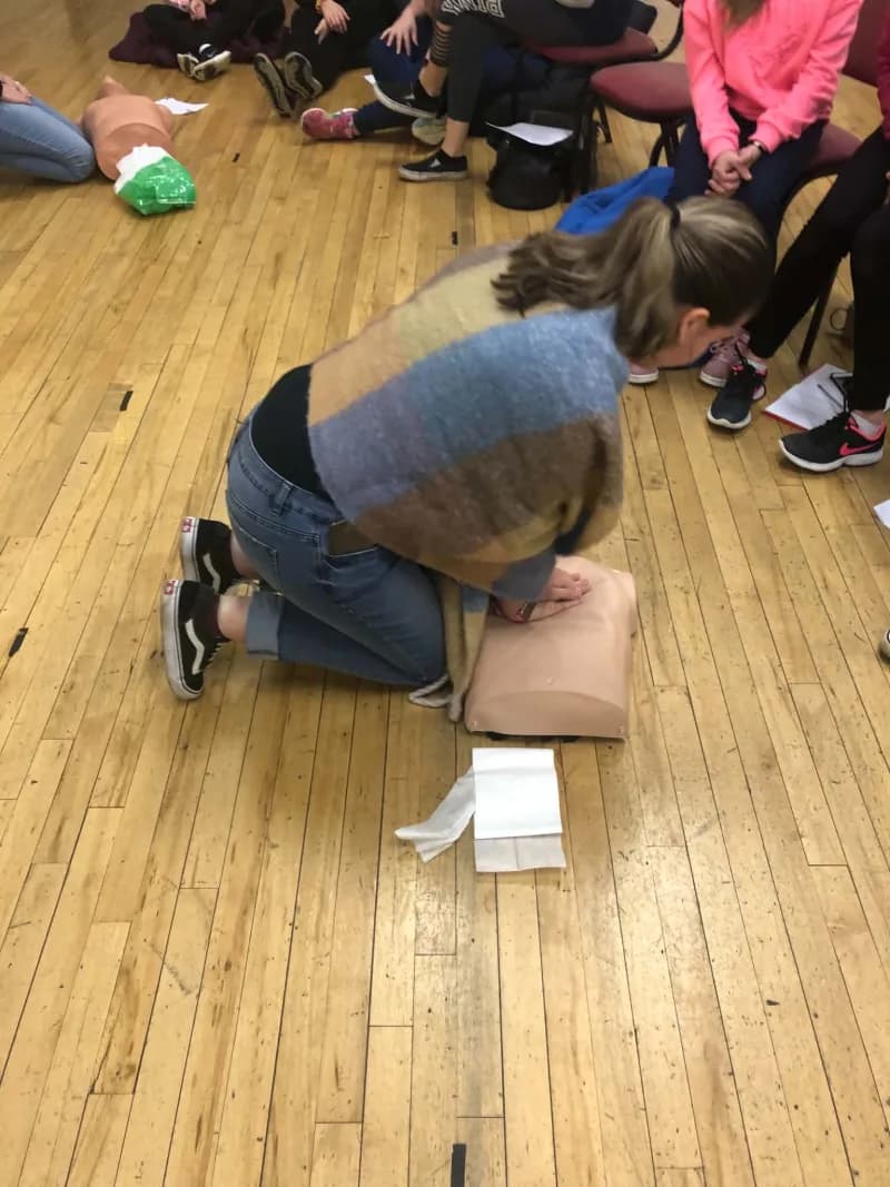 A participant practising CPR technique on a training mannequin